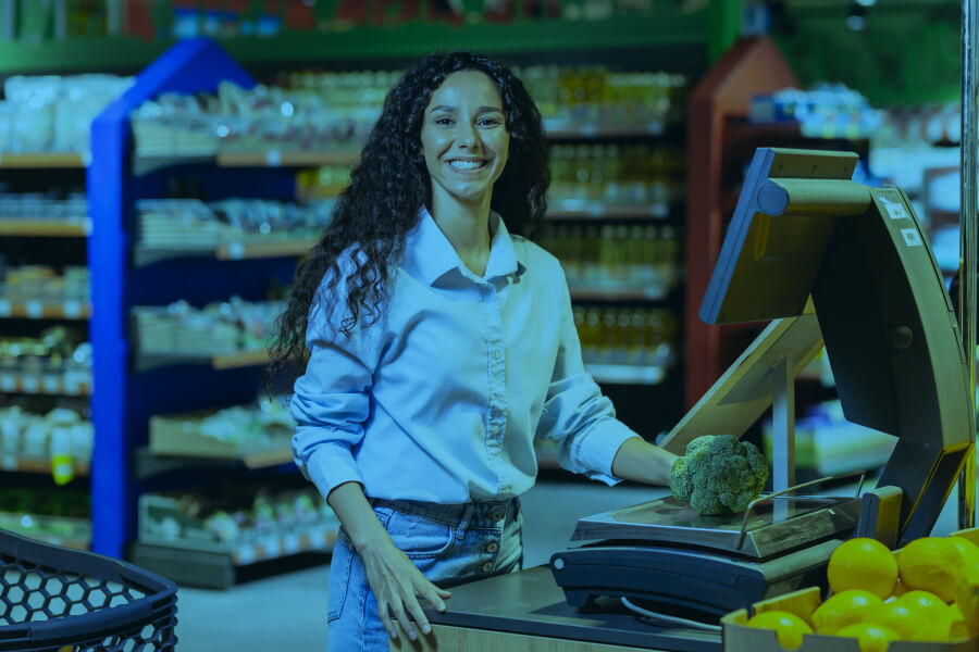 Tienda digital - Cajera sonriente atendiendo en supermercado.