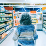 Precio en tienda - Persona comparando productos en estantería.