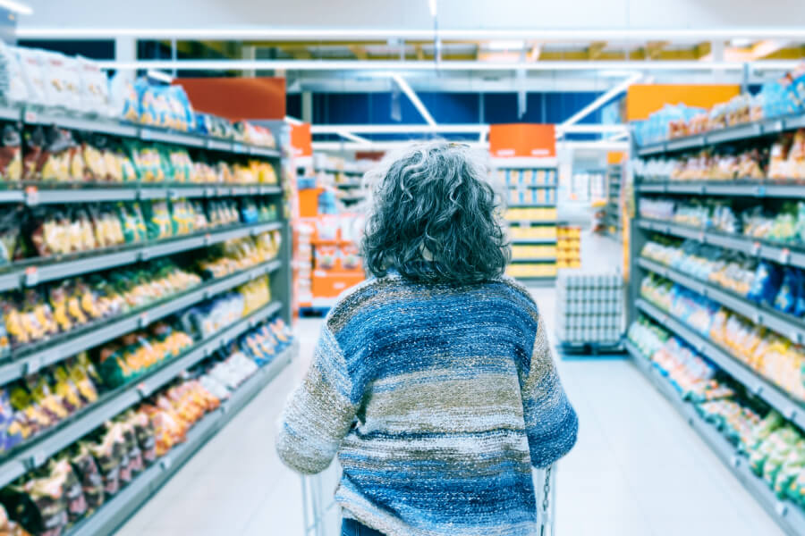 Precio en tienda - Persona comparando productos en estantería.