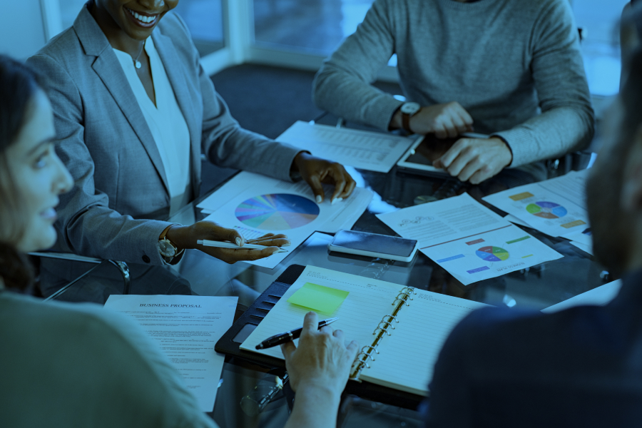 Equipo de trabajo reunido analizando documentos y datos en una mesa de oficina.